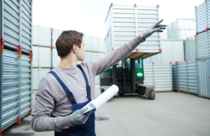 worker moving shipping container with forklift